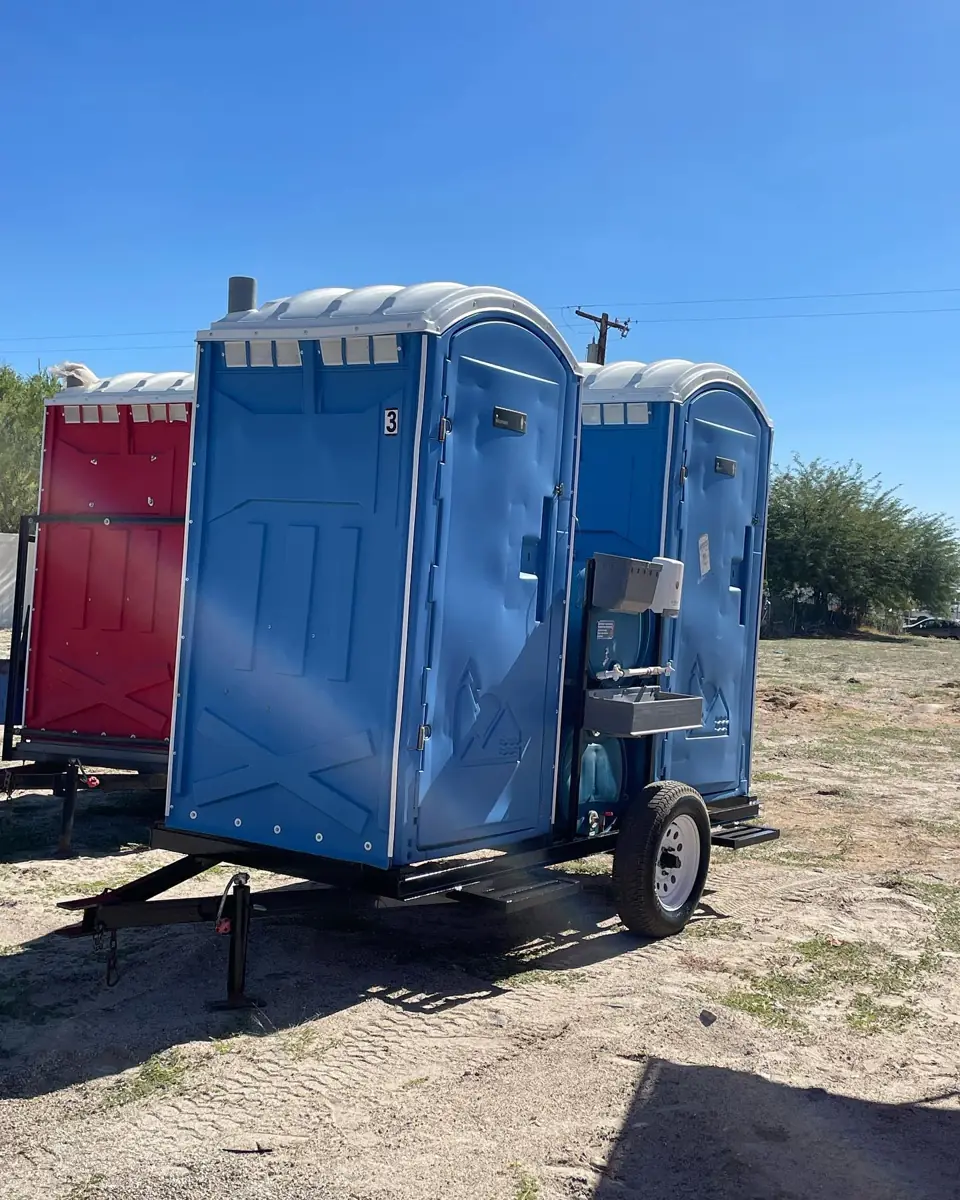 Two blue porta potties secured on a small towable trailer